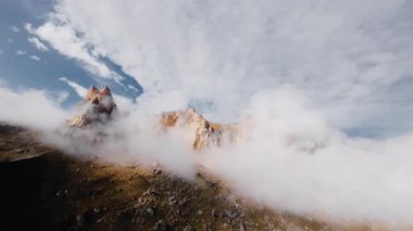 Hava sinemasının hava manzarası alçak bulutların arasında ve yanında destansı bir dağ arazisindeki kaya oluşumlarında dinleniyor..