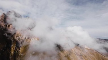 Hava sinemasının hava manzarası alçak bulutların arasında ve yanında destansı bir dağ arazisindeki kaya oluşumlarında dinleniyor..