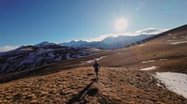 Spor giyimli bir adamın tarlalarda hızla koşarkenki görüntüsü. Dağlarda karla kaplanmış doğa sporu yapan bir adam. Bacaklarının altından bak, sağlıklı bir yaşam tarzı..