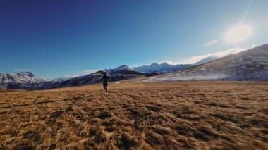 Spor giyimli bir adamın tarlalarda hızla koşarkenki görüntüsü. Dağlarda karla kaplanmış doğa sporu yapan bir adam. Bacaklarının altından bak, sağlıklı bir yaşam tarzı..