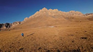 Spor giyimli bir adamın tarlalarda hızla koşarkenki görüntüsü. Dağlarda karla kaplanmış doğa sporu yapan bir adam. Bacaklarının altından bak, sağlıklı bir yaşam tarzı..