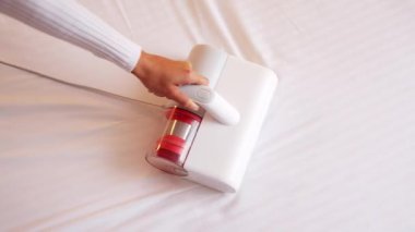 Elinde elektrikli süpürge olan bir kadın döşemeleri temizliyor. Toz ve akarlardan döşenmiş mobilyaları işliyor, temizliyor. Uyuduktan sonra yatağı temizlemek, ultraviyole ile elektrikli süpürge..