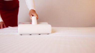 Çarşafları süpüren kadın. Tüm yatakları, kanepeleri ve yatak örtülerini temizlemek için ultraviyole ışığı olan elektrikli süpürgeler ve mikroplu toz akarları. Sağlık hizmetleri konsepti ev temizliği ve sağlık.