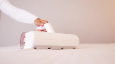 Elinde elektrikli süpürge olan bir kadın döşemeleri temizliyor. Toz ve akarlardan döşenmiş mobilyaları işliyor, temizliyor. Uyuduktan sonra yatağı temizlemek, ultraviyole ile elektrikli süpürge..