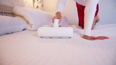 Çarşafları süpüren kadın. Tüm yatakları, kanepeleri ve yatak örtülerini temizlemek için ultraviyole ışığı olan elektrikli süpürgeler ve mikroplu toz akarları. Sağlık hizmetleri konsepti ev temizliği ve sağlık.