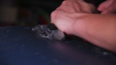 Fazla balmumundan snowboard yüzeyini temizliyorum. Snowboard tamiri. Kayak ekipmanlarının mevsimsel bakımı. Yakın plan..
