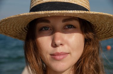 30 yaşında saman yeşili elbiseli gülümseyen Avrupalı bir kadının yakın plan portresi bulutlu bir gökyüzü ve denizin arka planında kameraya bakıyor. Güzel kız. Romantik bir ruh hali ve...