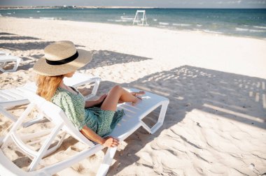 Güneşli bir yaz gününde lüks bir tropik plajda güneşlenen güzel bir kadın..