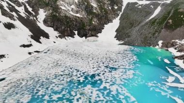 Dağlık tepelerin yakınındaki yüksek dağ gölü ve Alplerin ya da Kafkasların yüksek tepelerindeki kayalıklarda kar yamaları. Alp manzaraları. Taze suyun doğal kaynakları.