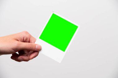 Fotoğraf çerçevesi kızların elinde. Kadın eliyle bastırılmış bir fotoğraf. Reklamınız için yakın plan. Hayattaki mutlu anların bir fotoğrafı. yeşil ekran