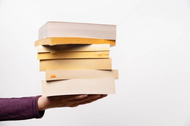 Elinde bir yığın kitap, bir elinde beyaz arka planda birkaç kitap. Ev tatili. Evde kendini izole etme. Evde eğitim.