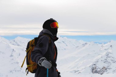 Kayak merkezi tatili. Adam karlı dağlarda dikilip manzaranın tadını çıkarıyor. Alplerde kayak yapan sporcu.
