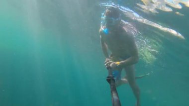 Suyun altında çekim yapan erkek arkadaşlar güneşli bir günde su altında şnorkelle yüzerler. Aksiyon kamerasından ilk kişi görüntüsü. Serbest dalış.