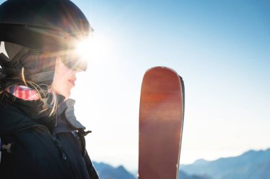 Kadın kayak gözlüklerinin karlı dağlara ve güneş ışınlarına karşı yakın çekimi. Kış sporları. Tatildeki mutlu kız..