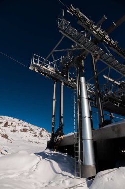 Kablolu araba istasyonu. Bulutsuz havada karlı dağlarda tek yönlü teleferik yapının geniş açılı görüntüsü.