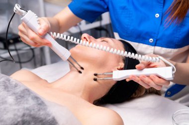 Boynunda elektrotlar olan genç bir kadının yakın çekimi. Kozmetoloji odasında.