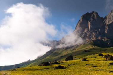 Dağların manzarası dramatik gökyüzü üzerine yapışmış, yeşil yemyeşil çimenler, dağlık çayırlar..