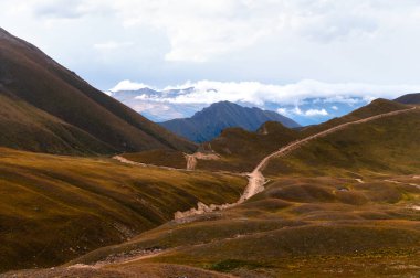 Göz kamaştırıcı dağ manzarası çok güzel. Bulutlu dağların önündeki çayır ile muhteşem panoramik manzara. Bulutlu bir günde Idyllic doğa manzarası.