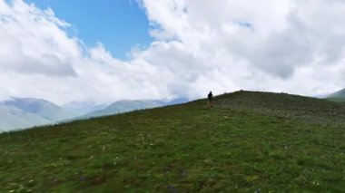 Erkek sporcu yaz mevsiminde dağlarda bir dağ manzarasının arka planında koşuyor. Hava görünümü spor içeriği