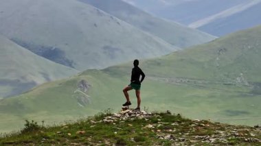Eğitim sırasında dağın zirvesinde olan sporcu, eğitimde başarılı oluyor. Heyecanlı enerjik bir adam, spor yapmak için açık havada, dağlara doğru koşuyor..