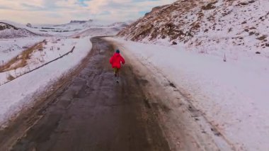 Akşam gün batımında koşu. Kışın dağlarda koşan erkek koşucunun hava görüntüsü..