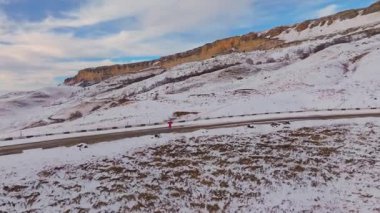 Akşam gün batımında koşu. Kışın dağlarda koşan erkek koşucunun hava görüntüsü..