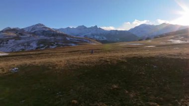 Spor görüntüleri, sonbaharda dağ sırtında koşan genç bir adamın karlı dağların büyüleyici manzarası. Dağlarda dayanıklılık eğitimi..