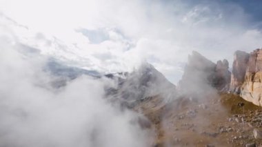 Hava manzaralı sinemalar bulutların arasında süzülür. Alçak bulutlar, destansı dağlık arazide kaya oluşumlarında yatar. Fpv İHA görüntüsü
