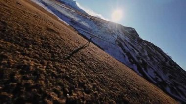 Sonbahar ya da kış aylarında dağ vadisinde arka planda dağlarla koşan spor giyimli FPV insansız hava aracı. Profesyonel koşucunun spor insansız hava aracı görünümü.