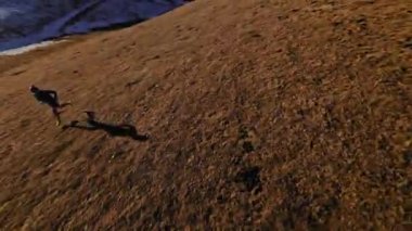 Spor giyimli bir adamın tarlalarda hızla koşarkenki görüntüsü. Dağlarda karla kaplanmış doğa sporu yapan bir adam. Bacaklarının altından bak, sağlıklı bir yaşam tarzı..