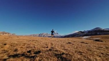 Spor giyimli bir adamın tarlalarda hızla koşarkenki görüntüsü. Dağlarda karla kaplanmış doğa sporu yapan bir adam. Bacaklarının altından bak, sağlıklı bir yaşam tarzı..