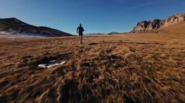 Spor giyimli bir adamın tarlalarda hızla koşarkenki görüntüsü. Dağlarda karla kaplanmış doğa sporu yapan bir adam. Bacaklarının altından bak, sağlıklı bir yaşam tarzı..
