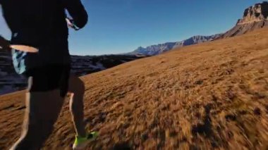 Spor giyimli bir adamın tarlalarda hızla koşarkenki görüntüsü. Dağlarda karla kaplanmış doğa sporu yapan bir adam. Bacaklarının altından bak, sağlıklı bir yaşam tarzı..