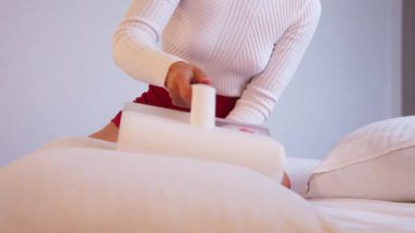 Beyaz kadın yatak akarlarından çarşaf temizliyor. Toz çarpma fonksiyonu ve ultraviyole dezenfeksiyonu olan bir yatak süpürgesi kullanıyor.