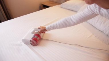 Elinde elektrikli süpürge olan bir kadın döşemeleri temizliyor. Toz ve akarlardan döşenmiş mobilyaları işliyor, temizliyor. Uyuduktan sonra yatağı temizlemek, ultraviyole ile elektrikli süpürge..