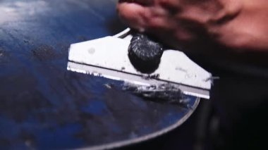 Snowboard tamircisinin kadın elleri kayan bir kayak yüzeyinden balmumu temizliyor. Sığ alan derinliğiyle yakın çekim. Alçak tuş.