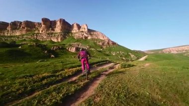 Motosikletli birinin toprak yolda dağ bisikleti sürerken çekilmiş bir FPV görüntüsü. Erkek bisikletçinin dağlardaki doğa sporunun en üst görüntüsü.