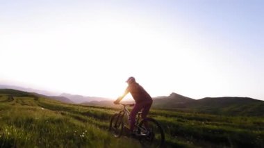 Motosikletli birinin toprak yolda dağ bisikleti sürerken çekilmiş bir FPV görüntüsü. Erkek bisikletçinin günbatımında dağlarda doğa sporu yapması.