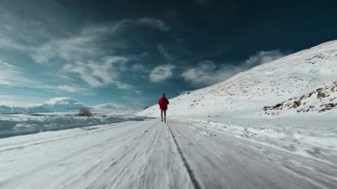Profesyonel atlet dağlarda karlı asfalt yolda koşar. Kışın yüksek irtifada kardiyo eğitimi.