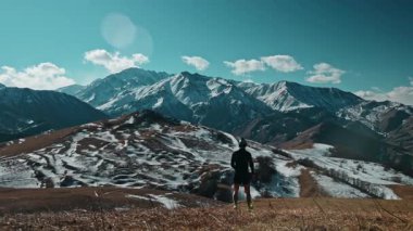 Güneşli bir sonbahar gününde dağlarda yokuş aşağı inen beyaz erkek sporcu. Arkadan görüntüle.