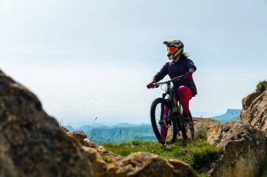 Bisikletli tanınmaz bir adam. Dağ bisikletçisi yaz aylarında dağ manzarasında at sürdükten sonra ayakta duruyor. Açık hava sporları.