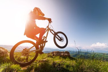 Genç adam arka tekerlekte dağ bisikletiyle havada süzülüyor. Fitness, ekstrem sporlar ve açık havada bisiklet, atlama ve macera için bir adamla dağ bisikleti. Adrenalin müptelası, performans ve sporcuyla birlikte açık havada eylem için gösteri yapıyor.