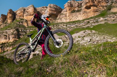 Bisiklet kasklı sporcu, destansı dağların ve manzaranın arka planına inmeden önce ayakta ve dinleniyor. MTB disiplin geçmişi. Dağ bisikleti için alan kopyalama arka planı.