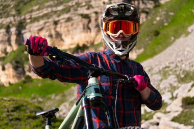 Kasklı bisikletçi ve bardaklar kayalık keskin dağların arka planında. Dağlarda ekstrem yaz bisikleti.