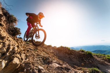Kasklı ve koruyucu maskeli bir erkek bisikletçi. Dağlık arazide MTB sürücüsü destansı kayaların arka planına karşı