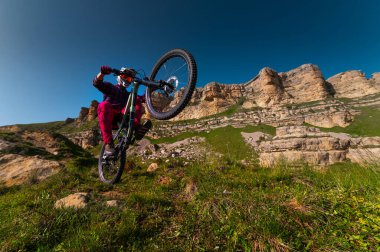 Bisiklet süren bir bisikletçi. Dağ bisikleti kayalık bir patikaya iniyor. Ekstrem sporlar ve dayanıklı kavramlar. Arka tekerde hile var..