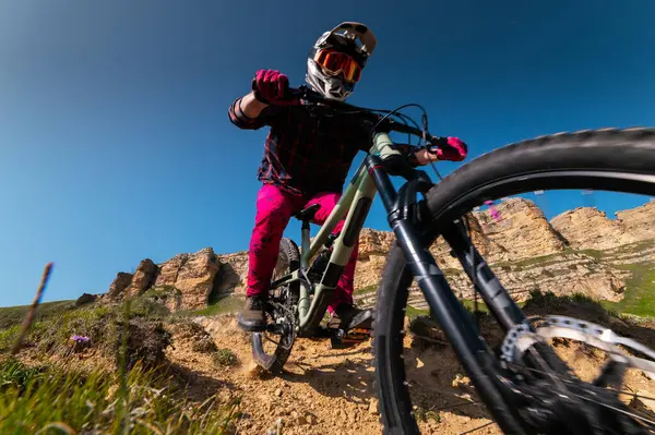Kasklı ve koruyucu maskeli bir erkek bisikletçi. Dağlık arazide MTB sürücüsü destansı kayaların arka planına karşı