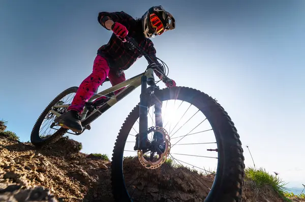 Dağ bisikletçisi çimenli bir yamaçtan aşağı iniyor. Enduro dağ bisikleti. Bir dağ manzarasına karşı MTB.