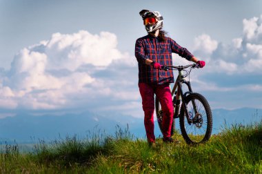 Kümülüs bulutlu dramatik bir gökyüzüne karşı bisikletiyle duran bir bisikletçinin portresi. Kırsalda bisiklete binen yakışıklı genç adam..