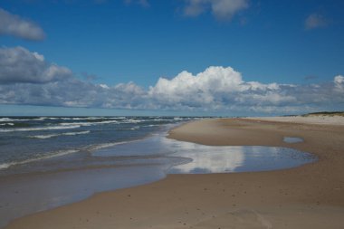 Beautiful seaside landscape, an empty beach, the foamy water of the Baltic Sea, blue sky with white clouds. Slowinski National Park, Poland. clipart